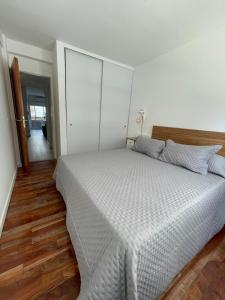 um quarto com uma cama branca e piso em madeira em Temporario 48 em La Plata