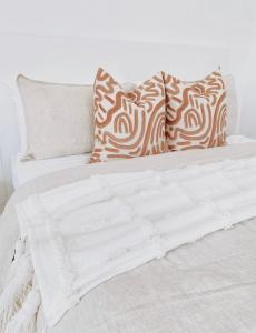 Una cama blanca con almohadas marrones y blancas. en The Hideaway - Guest House en Warrnambool