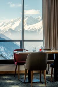 ein Esszimmer mit Blick auf die schneebedeckten Berge in der Unterkunft Madame Vacances Hotel Les Cimes in Vaujany