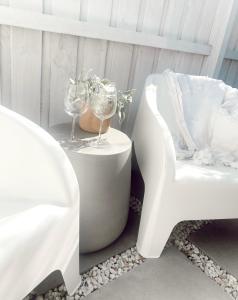 a white chair and a table with wine glasses on it at The Hideaway - Guest House in Warrnambool