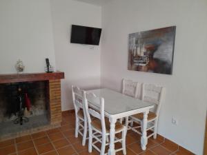 comedor con mesa, sillas y chimenea en Casa Rural La Maestra, en Ronda