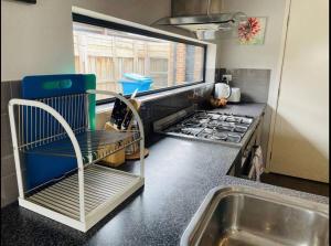 una cocina con fregadero y una silla junto a una estufa en Sweet four bedroom home @cranbourne west, en Cranbourne