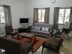 a living room with a couch and chairs and a tv at KJS Homestay, Layang-Layang, Johor in Kangkar Lanjut
