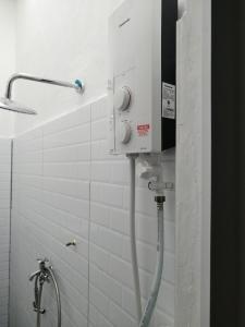 y baño con ducha y pared de azulejos blancos. en KJS Homestay, Layang-Layang, Johor, en Kangkar Lanjut
