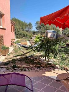 una sombrilla roja y una silla frente a un edificio en Charmant petit appartement proche du pic St loup, en Le Triadou