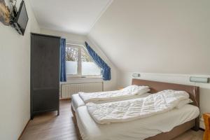 - 2 lits dans une petite chambre avec fenêtre dans l'établissement Villapark Kamperfoelie 43, à De Koog