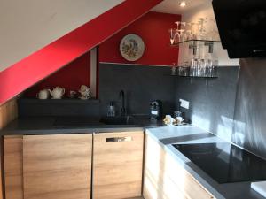 a kitchen with a black counter and a red wall at Appartement Cosy Chelles in Chelles