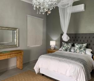 a bedroom with a bed and a mirror and a chandelier at Hazyview Accommodation, Bon Repose Cottages 3&4 in Hazyview