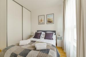 a white bedroom with a large bed with purple pillows at Apartament SEAGRASS SurfingBird Dźwirzyno in Dźwirzyno