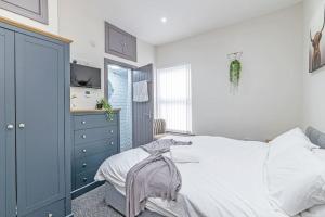 a bedroom with a white bed and a blue cabinet at 3 Bedroom Holiday House in Liverpool