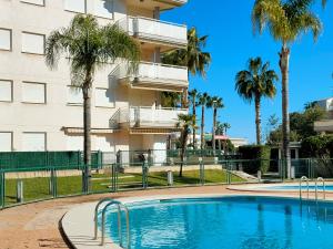 uma piscina em frente a um edifício com palmeiras em Global Properties, Apartamento con terraza en Canet de Berenguer em Canet d'En Berenguer