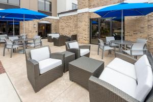 eine Terrasse mit Tischen, Stühlen und blauen Sonnenschirmen in der Unterkunft Holiday Inn Express & Suites Wadsworth, an IHG Hotel in Wadsworth