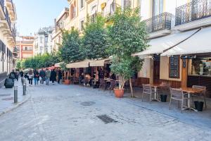 un grupo de personas caminando por una calle con mesas y sillas en AlohaMundi Catedral, en Sevilla