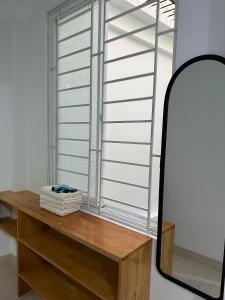 einen Spiegel neben einem Fenster mit einem Holztisch in der Unterkunft Q House- Green Villa Quy Nhơn in Quy Nhon