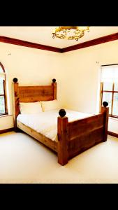 a bedroom with a wooden bed in a room with windows at Ridge Wood House in Armagh