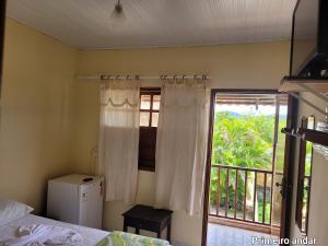 1 dormitorio con 1 cama y ventana con balcón en Pousada Betta, en Pirenópolis