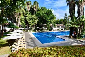 a swimming pool with chairs and umbrellas in a resort at Hotel Kabila in M'diq