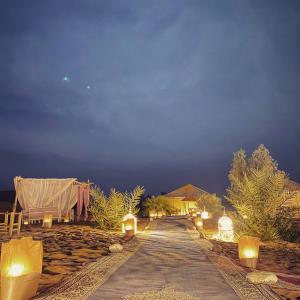 un camino que conduce a un complejo por la noche con luces en Bohemian Camp, en Merzouga
