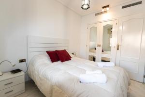 een witte slaapkamer met een groot wit bed met rode kussens bij 073 - Puerto Varadero 001 - comfortHOLIDAYS in Santa Pola