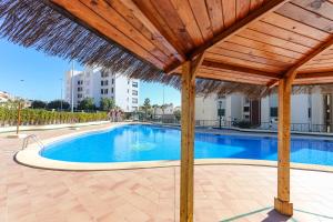 een groot zwembad met een rieten parasol en een zwembad bij 073 - Puerto Varadero 001 - comfortHOLIDAYS in Santa Pola
