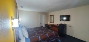 ein Hotelzimmer mit einem Bett und einem Flachbild-TV in der Unterkunft American Inn Motel in Pratt