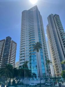 a tall building with palm trees in front of it at 2703 Flat Beira Mar Av Boa Viagem com Cozinha in Recife