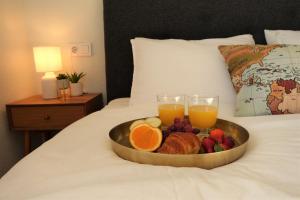 uma bandeja de frutas e dois copos de sumo de laranja numa cama em Boutique Hotel Colina del Emperador em La Manga del Mar Menor