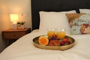 una bandeja de fruta y dos vasos de zumo de naranja en una cama en Boutique Hotel Colina del Emperador, en La Manga del Mar Menor