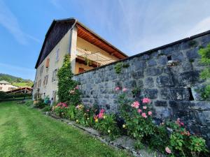 a stone wall with flowers in front of a building at La belle des praz in Mieussy