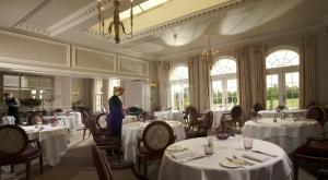 a woman standing in a dining room with tables at Brockencote Hall in Kidderminster
