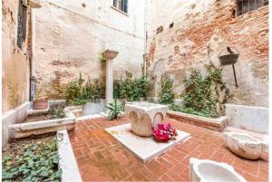 a courtyard with a fountain and flowers in a building at La Dogaressa Guest House in Venice
