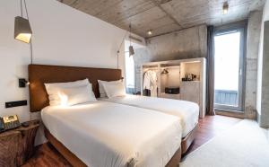 a bedroom with a large white bed and a large window at Hotel Cajú in Funchal