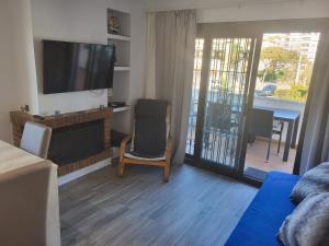 uma sala de estar com uma televisão de ecrã plano e uma cadeira em Can Kuqueta, Platja d'Aro em Platja  d'Aro