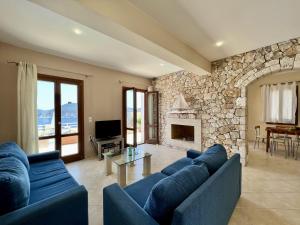 a living room with blue couches and a stone fireplace at Villa Fiscardo View Fiscardo Kefalonia in Mánganos