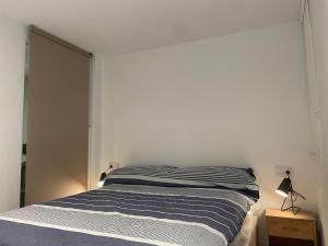 1 dormitorio con cama y pared blanca en WASELA 114, en Palamós