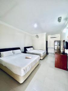 a bedroom with two beds and a flat screen tv at Kenangan Inn in Pantai Cenang