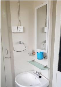 a white bathroom with a sink and a mirror at J & I Homestay B 3 Person with shared bathroom in Sibu