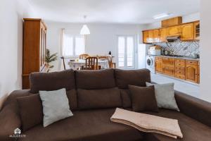 a living room with a brown couch and a kitchen at Apartamento Miramar - Piscina e BBQ in Santa Cruz