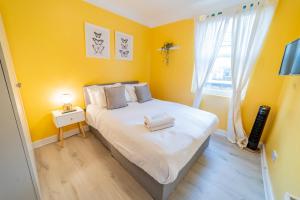 Un dormitorio con una cama con paredes amarillas y una ventana en [COVENT GARDEN] Apartment in Central London en Londres
