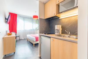 - une cuisine avec évier et un lit dans une chambre dans l'établissement Appart’City Confort Montpellier Millénaire, à Montpellier