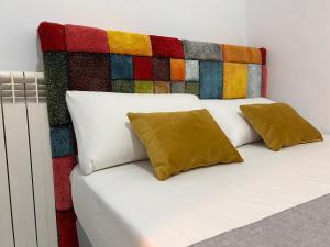 a bed with two pillows and a colorful headboard at CH Barco in Madrid