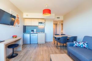 a living room with a blue couch and a kitchen at Appart’City Confort Montpellier Millénaire in Montpellier