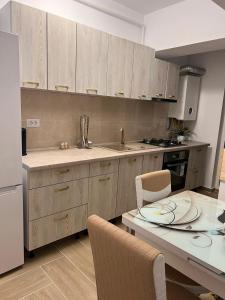 una cocina con armarios de madera y una mesa con sillas. en Apartament 2 camere Proximitate Aeroport, en Iaşi