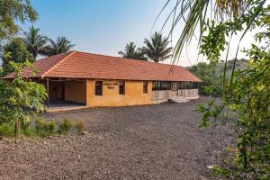 a small yellow house with a red roof at CosmicStays Rustic Elegance - Traditional Wada Inspired Living in Shirwal
