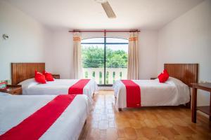 1 dormitorio con 2 camas con almohadas rojas y ventana en OYO Hotel Arena Surf, Puerto Escondido, en Puerto Escondido