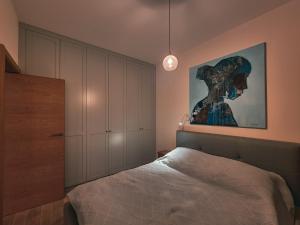 オルシュティンにあるApartament Villa Łyna Parkのベッドルーム1室(ベッド1台付)が備わります。壁には絵画が飾られています。