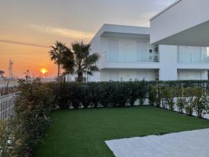 a house with a lawn in front of it with the sunset at JESOLO GROUND FLOOR FLAT WITH POOL - 2 family apartments in Lido di Jesolo