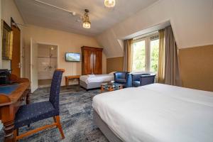 a hotel room with a bed and a desk and chairs at Fletcher Hotel Apeldoorn in Apeldoorn