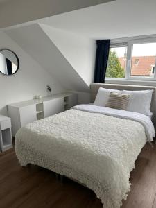 a white bedroom with a large bed with a window at Central Suite Rotterdam in Rotterdam