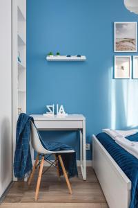 a blue bedroom with a desk and a bed at Apartment Leśne Tarasy Dziwnówek by Renters in Dziwnówek